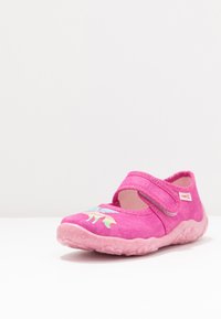 Różowe buty z tkaniny o zaokrąglonym kształcie, wzmocnionym nosku, regulowanym pasku i lśniącej gumowej podeszwie. Zawierają wielokolorowy wzór dinozaurów.