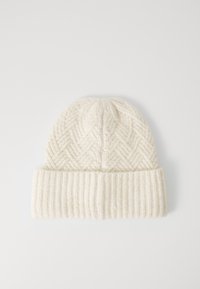 Gorro de lana tejido en color blanco roto con ala acanalada doblada y patrón en chevrón texturizado en la corona, sobre un fondo liso.