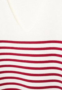 Punaiset ja valkoiset raidalliset neulepuserot, joissa on V-kaulus. Kangas on pehmeä ja siinä on vaakasuoria raitoja, joiden leveydet vaihtelevat.