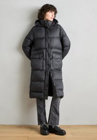 Must must probleematu must coat, mis ta on must veidi paardel suured tasud, kaua nurgas, ja küljes on kaks koti kui kasutuselt. Kuidas rummud esindavate hallide kulumiskeebitega jeanide ja mustade paksude jalanõudega.