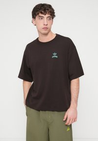 Μαύρο βαμβακερό t-shirt με άνετη εφαρμογή, με τουρκουάζ λογότυπο στο στήθος. Κοντά μανίκια και στρογγυλή λαιμόκοψη. Απλός σχεδιασμός.