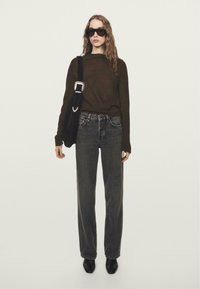 Top marrone a maniche lunghe, jeans grigi a vita alta, occhiali da sole neri, borsa nera con tracolla e scarpe nere appuntite. Design semplice e vestibilità rilassata.