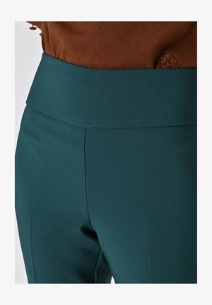 Pantaloni teal a vita alta realizzati in tessuto liscio, con una cintura morbida e cuciture pulite, progettati per un look aderente.