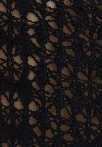 Svart spets tyg med ett intrikat, geometriskt mönster med öppna vävningar och en mjuk textur, vilket gör att huden syns under.