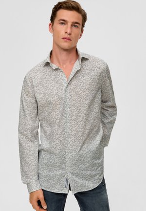 Langarmshirt aus leichtem Stoff mit geometrischem Druck in Blau. Klassischer Kragen, durchgehende Knopfleiste und abgerundeter Saum. Getragen mit dunklen Jeans.