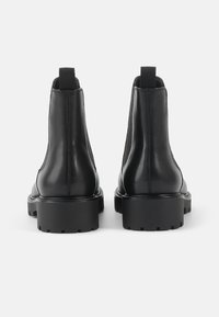 Zwarte leren enkellaarsjes met een gladde afwerking, elastische zijkanten en een chunky rubberen zool. Ontwerpdetails zijn de trekflappen aan de achterkant.