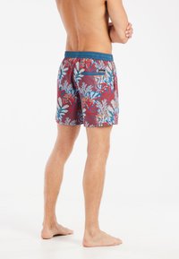 Zwemshorts voor mannen met een rode achtergrond, voorzien van een kleurrijke koraal- en bladenprint, een elastische tailleband en één achterzak.