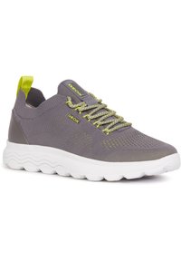 Zapatilla gris con parte superior de malla transpirable, acentos en verde lima contrastantes, patrones texturizados y una suela blanca acolchada. Logo de Geox visible.