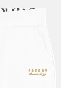 Pantalones de chándal blancos con una textura suave, que cuentan con una cintura con un patrón en blanco y negro y un detalle del logo dorado "FREDDY Training".