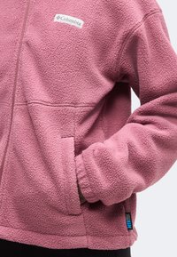 Ροζ ζακέτα fleece Columbia με μπροστινή τσέπη, ορατό λογότυπο στο στήθος και υφή μαλακού υφάσματος.