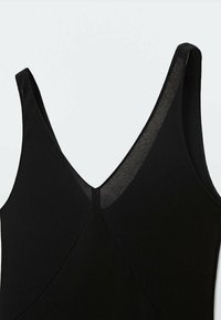 Robe sans manches noire avec un décolleté en V, présentant un tissu texturé et un design sans couture. Coupe simple et élégante.