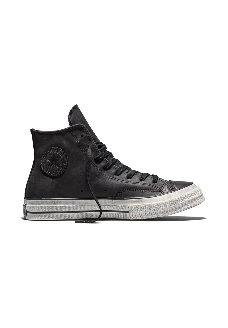 Black high-top leather sneaker with white rubber sole and black laces, showing side profile with visible brand logo patch.