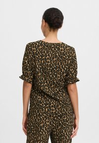 Top s leopardím vzorem a krátkými nabíranými rukávy, vyrobený z lehkého materiálu. Design obsahuje černé pozadí s hnědými skvrnami.