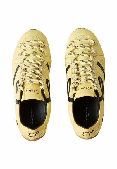 Par de zapatillas de cuero amarillo con detalles de swoosh negro, cordones a rayas y la marca "Claudie Pierlot Paris" en la lengüeta y la lengüeta del talón.