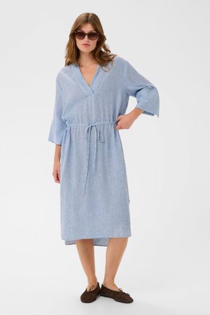 Triibuline sinise ja valge kleit, V-kaeluse, pihaosast kokku tõmmatud vöö ja kolmejärguliste kellukeste varrukatega. Pehme, kerge kangas; põlveni ulatuv.