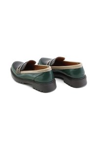 Zapatos de cuero sin cordones con parte superior de color verde oscuro, acentos en color marrón claro y suela negra texturizada. Presentan una punta redondeada y detalles con bordes ondulados.