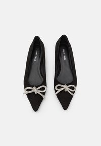 Ballerines noires en suede à bout pointu avec un accent décoratif de noeud en rhinestones à l'avant. Doublure intérieure lisse avec le nom de la marque à l'intérieur.