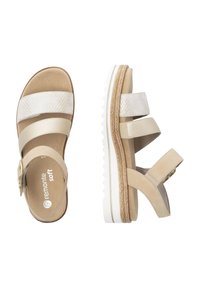 Beige sandals with woven white straps, two adjustable buckles, and a layered textured sole. Soft material, low heel, and modern design.