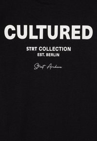 Černé bavlněné tričko s odvážným bílým textem: "KULTIVOVANÝ," "STRRT KOLEKCE," "ZALOŽENO V BERLÍNĚ" a "Street Archive," s různými styly písma.