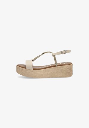 Sandalia plataforma con suela de yute trenzada, correas de cuero crema y una correa metálica en el tobillo. Presenta una superficie texturizada y un diseño minimalista.