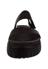 Sandal de plataforma negra con tiras anchas y diseño de punta abierta. Suela texturizada con profundas ranuras para mayor tracción. Estilo minimalista.