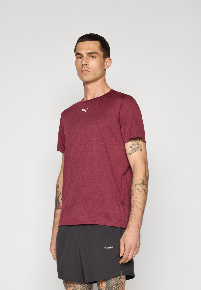 Bordeauxfarbenes Sport-T-Shirt aus leichtem, atmungsaktivem Material, mit Rundhalsausschnitt und kurzen Ärmeln, sowie einem kleinen weißen Puma-Logo auf der Brust.