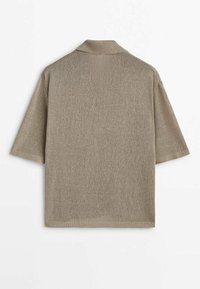 Short-sleeved polo shirt in light beige knit fabric, featuring a classic collar and ribbed hem. Simple design with no visible patterns or hardware.