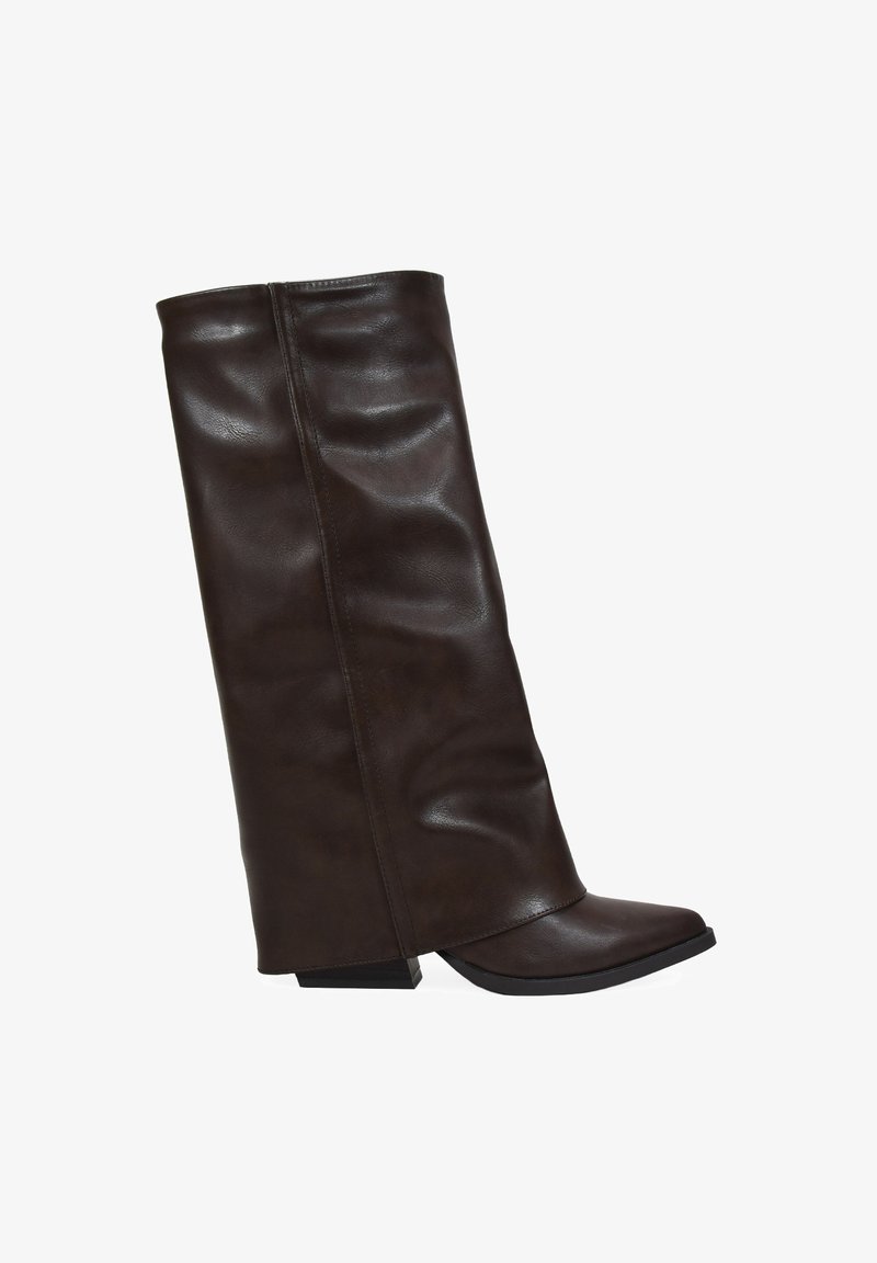 Bota de cuero marrón oscuro alta con un eje ligeramente caído y tacón bajo en cuña, con la punta en ángulo, sobre un fondo blanco.