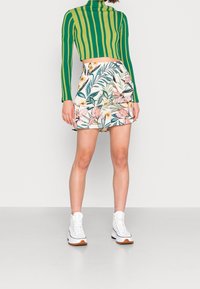 Zeleno-žlutý pruhovaný rolák, zkombinovaný s květinovou sukní se vzorem růžových květů a zelených listů. Bílé platformové tenisky.