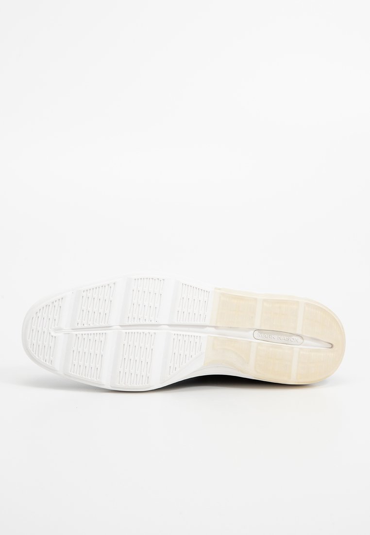 Sohle eines überwiegend weißen Sneakers mit strukturiertem Griff und "Mark Nason" eingraviert auf dem beigen Fersenbereich.