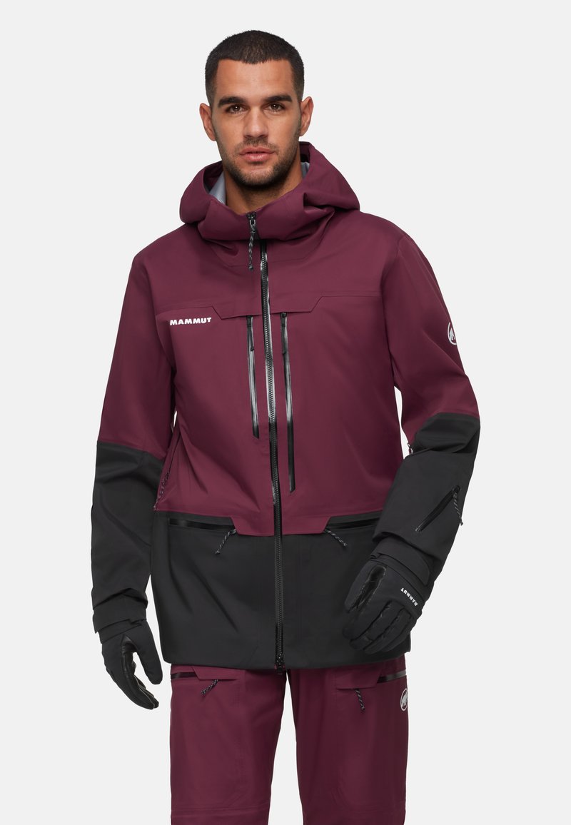 Kastanienbraune und schwarze wetterfeste Jacke mit Kapuze, mit Reißverschlusstaschen und Handschuhen, die ein schlankes, modernes Design aufweist.