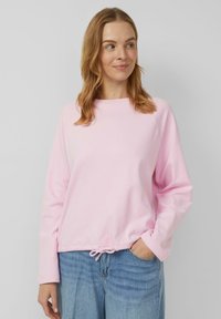 Jasnoróżowa bluza z okrągłym dekoltem i długimi rękawami. Dolny ściągacz z troczkiem dla regulowanego dopasowania. Miękka tekstura, luźny krój.