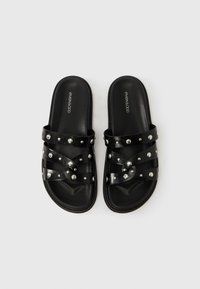 Μαύρα σανδάλια τύπου slides με λουριά που διασταυρώνονται και διακοσμημένα με ασημένια καρφιά, επίπεδη σόλα και λογότυπο "even&odd" στη σόλα, εμφανιζόμενα σε λευκό φόντο.