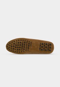 Semelle de chaussure en daim marron avec des clous en caoutchouc noir disposés en grappes horizontales pour l’adhérence et la durabilité.