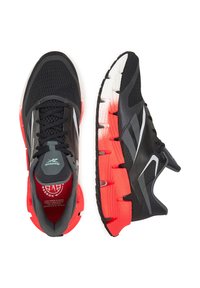 Čierne a červené bežecké topánky Reebok s mesh vrchom a segmentovanou podrážkou, zobrazené z horného a bočného pohľadu na bielom pozadí.