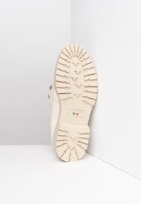 Beige rubber shoe sole with a textured, ridged surface and subtle pattern. Includes a label stating "NeroGiardini, Made in Italy."