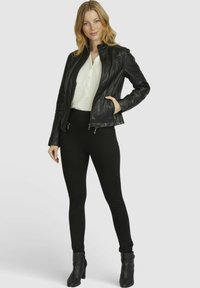 Black leather jacket with a zip closure, ribbed texture, and side pockets, paired with fitted black pants and ankle boots.