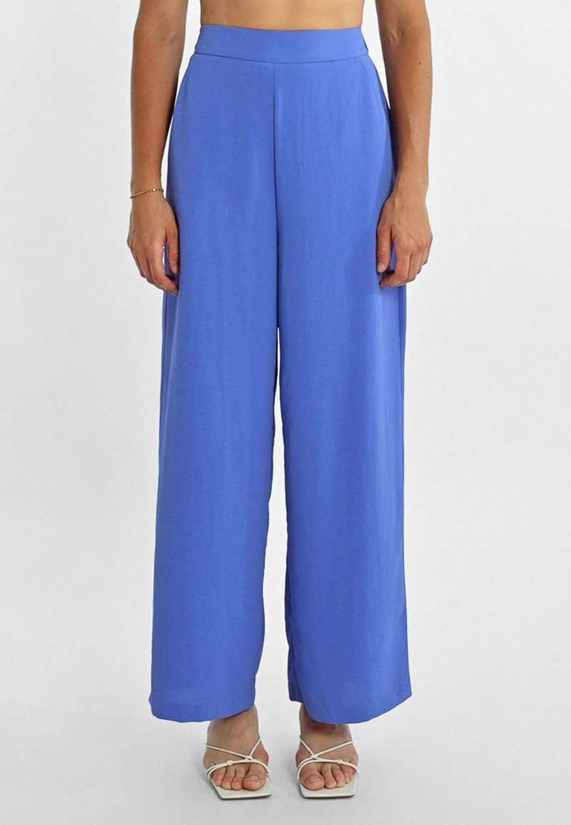 Pantaloni a gamba larga blu realizzati in un tessuto morbido e leggero. Vita alta con finitura piatta, caratterizzati da una vestibilità ampia e un taglio dritto.