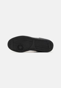 Black rubber shoe sole with a textured, zigzag pattern and circular accent in the center. The sole features deep grooves for traction.