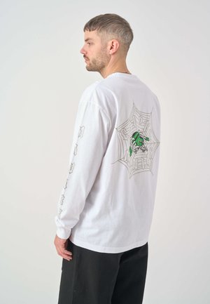 White long-sleeve t-shirt featuring a spider web graphic and a green character on the back, with text detail on the sleeves.