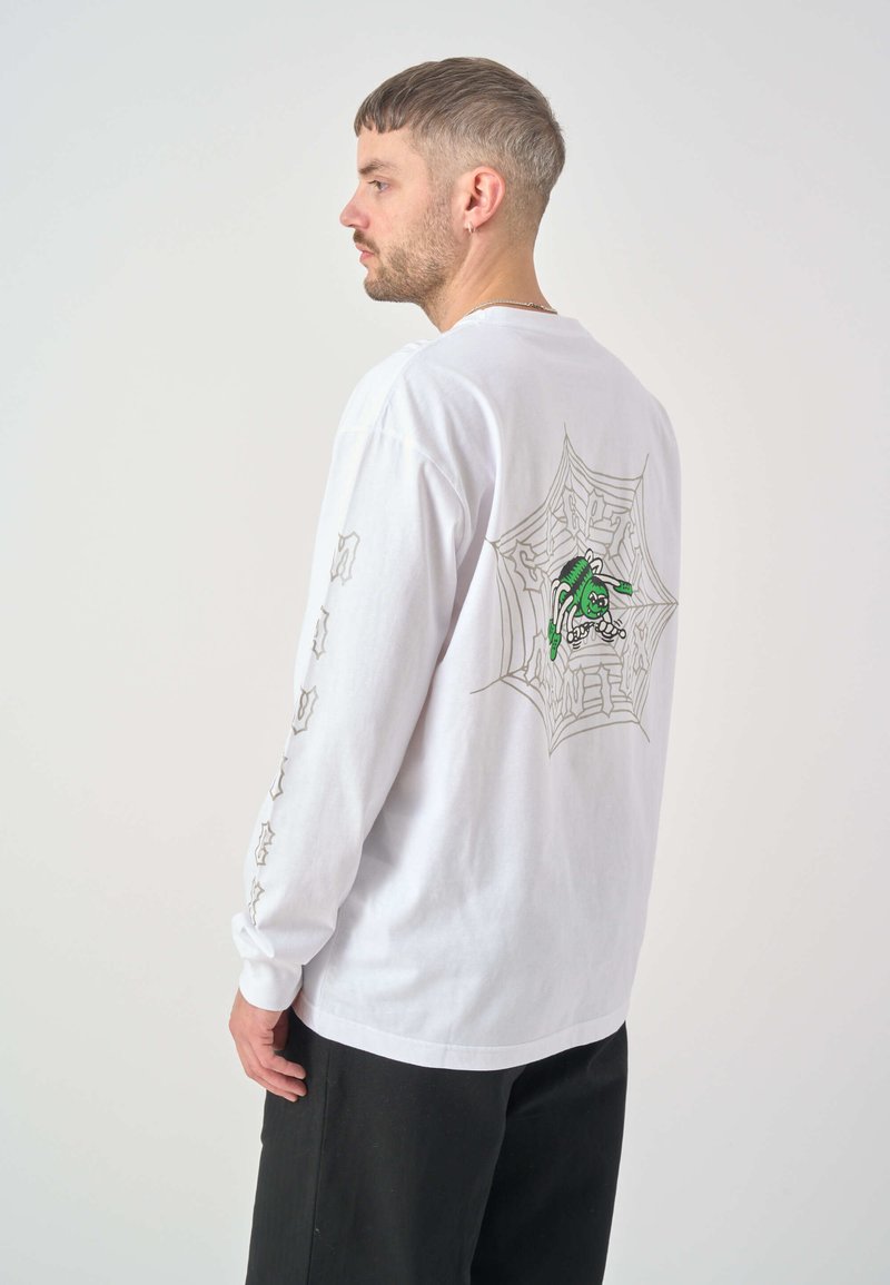 Weißes Langarm-T-Shirt mit einem Spinnennetzgrafik und einer grünen Figur auf dem Rücken, mit Textdetails auf den Ärmeln.