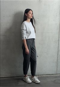 Grijze trui en grijze geblokte tapered broek, gecombineerd met witte sneakers. Zachte stof met ribgebreide manchetten en zijzakken.