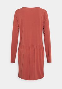 Vestido de mangas longas em terracota, com decote redondo, cintura franzida e textura de tecido suave. Sem padrões ou materiais visíveis.
