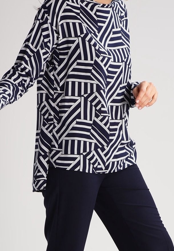 Marinblå långärmad tröja med ett geometriskt vitt randigt mönster. Löst sittande med rund halsringning och en asymmetrisk nederkant.
