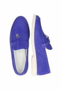 Mocassini in suede blu con suola in gomma bianca, dotati di un piccolo fiocco e di un accento in metallo con il logo. Texture liscia con una forma della punta arrotondata.