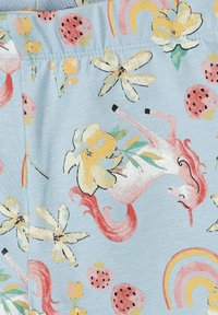 Tissu bleu doux avec des licornes roses, des fleurs jaunes, des fraises et des arcs-en-ciel pastel dans un motif ludique.