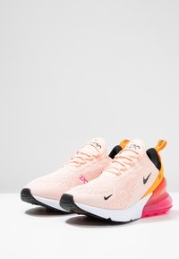 Tenisky Nike Air Max s lehkým růžovým síťovaným svrškem, černými akcenty, oranžovou patní částí a viditelnou vzduchovou jednotkou v růžové barvě.