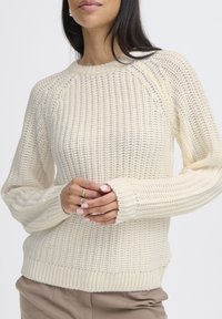 Strickpullover in Creme mit lockerer Passform, gerippten Bündchen und Saum sowie einem strukturierten Muster. Lange Ärmel mit Rundhalsausschnitt.