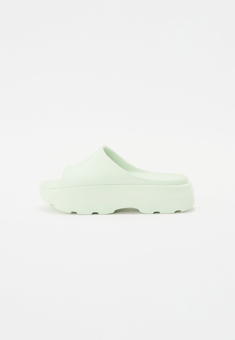 Sandálias slip-on verde menta com uma superfície suave e mate e uma sola grosso com um padrão texturizado para aderência.