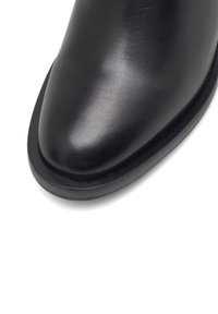 Mustusest nahast kingad, millel on sile viimistlus, ümar varvas ja tugev must tald. Saumidevaba disain, ilma nähtavate kinnitusdetailide või mustriteta.